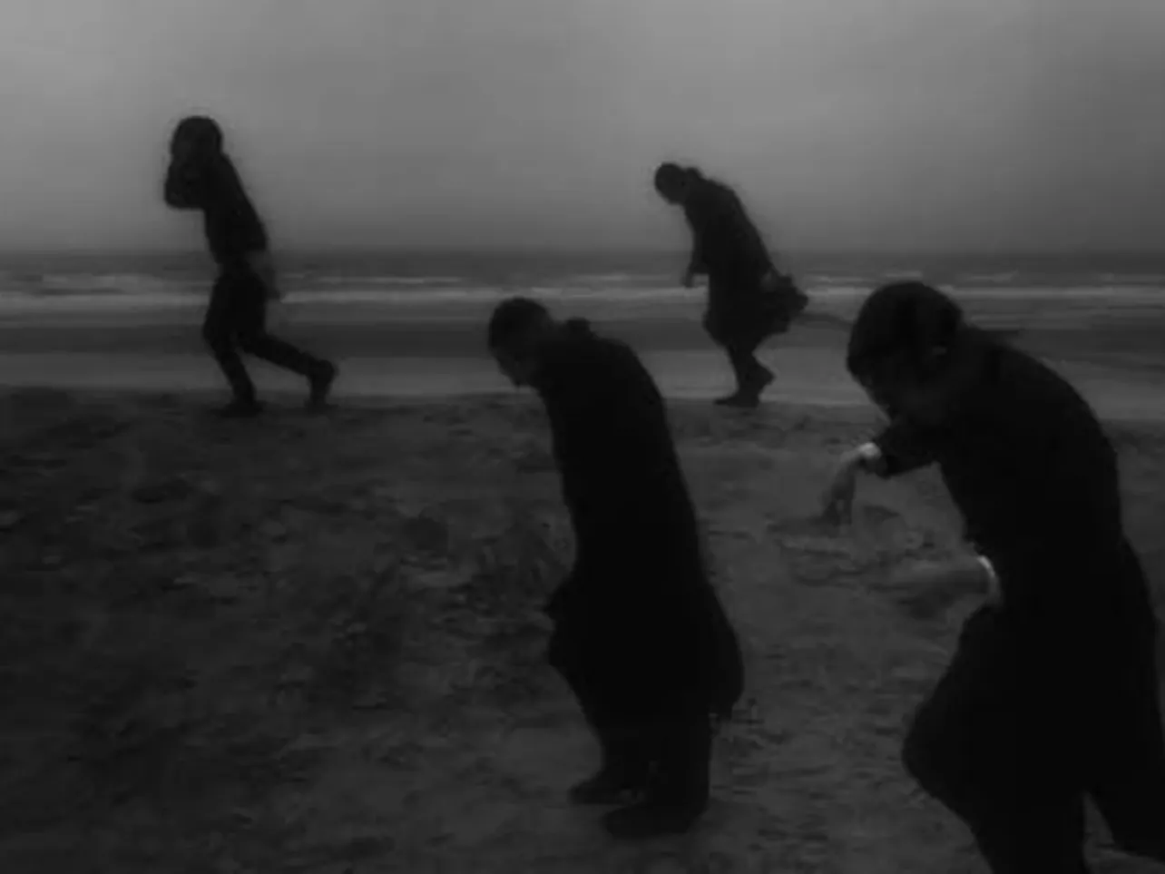 Vier donkere figuren trotseren een storm op het strand van Bredene, gefotografeerd door Eddy Verloes.
