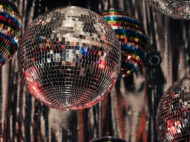 Discoballen en glinsterende achtergrond bij de tentoonstelling DISCO in Wereldmuseum Amsterdam.
