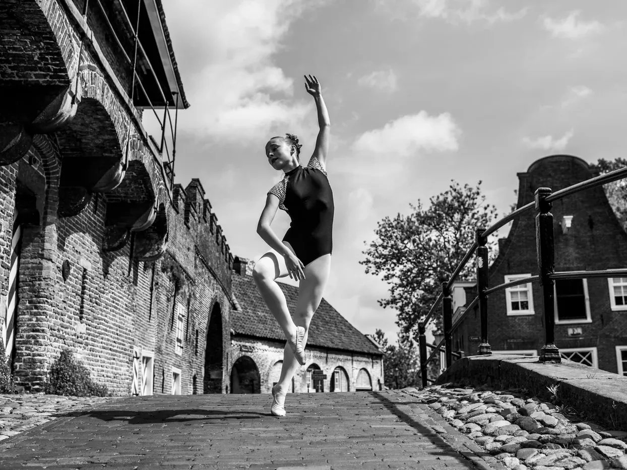 Zwart-witfoto van een danseres bij een bakstenen muur in Amersfoort.