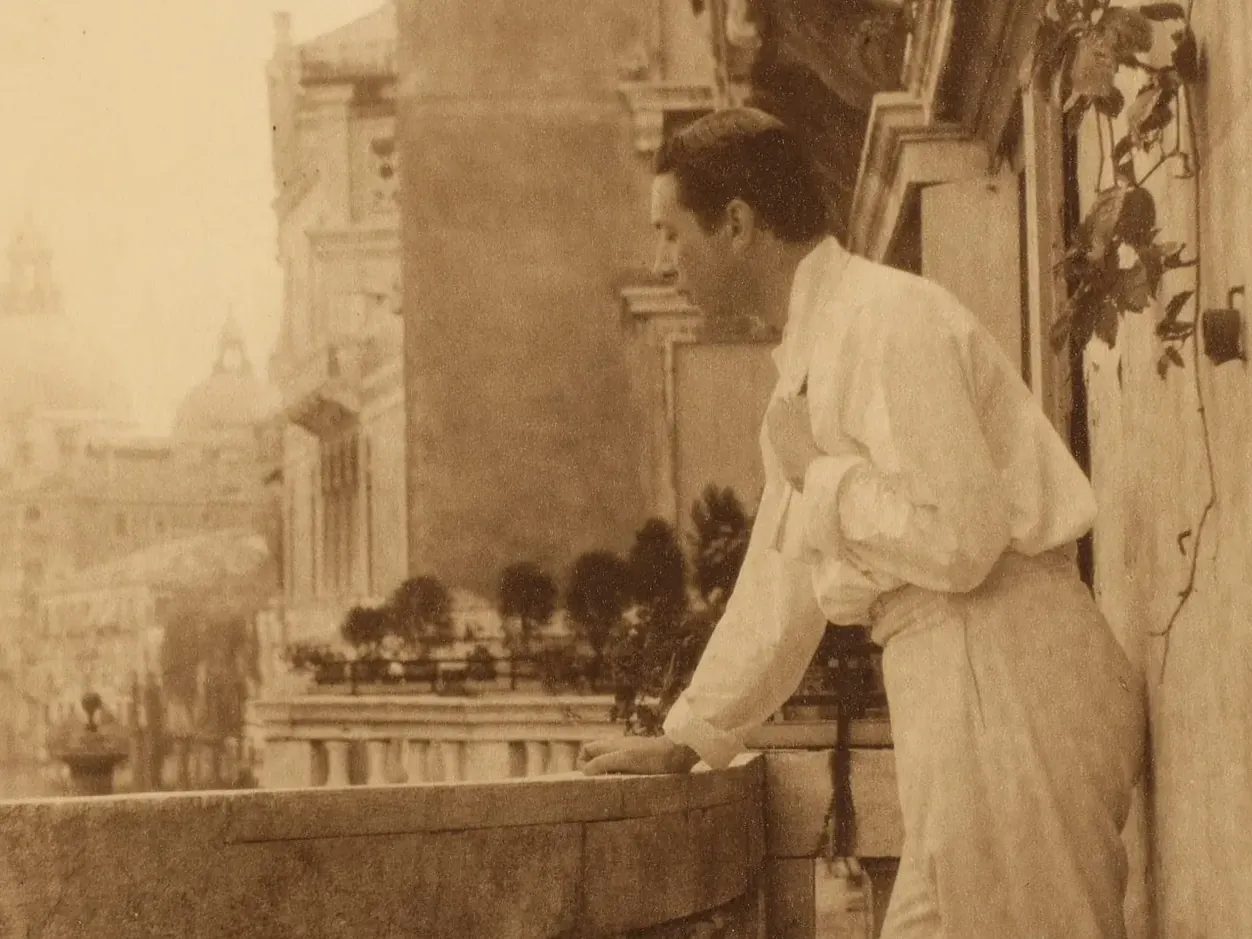 Sepiakleurig portret van Adolphe de Meyer, staand op een balkon van Palazzo Balbi-Valier in Venetië.