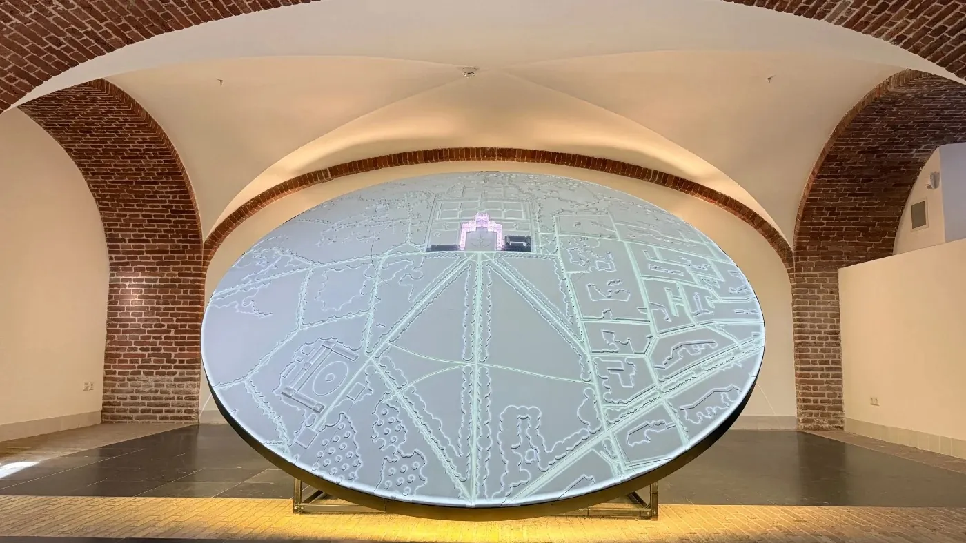 Een grote ronde, verlichte installatie in een binnenruimte met bakstenen gewelven.