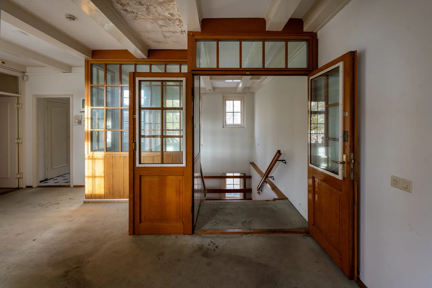 Wooden glazed doors and a stairwell inside the empty Walenweeshuis, photographed by Roos Aldershoff.