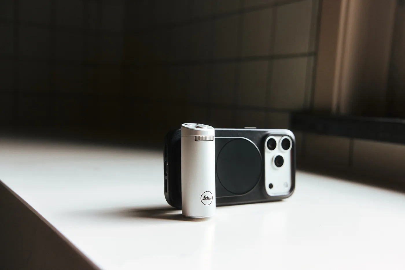 iPhone met een zilverkleurige Leica LUX Grip op een tafel