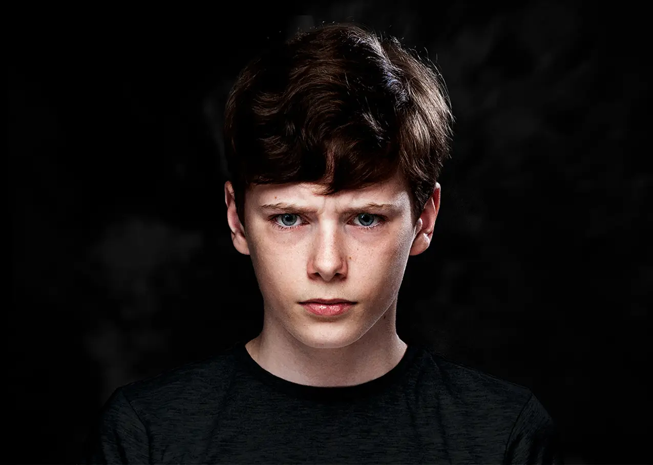 Portrait of a young person in a black shirt against a dark background, from Wat we meedragen by Metin Yirtici.