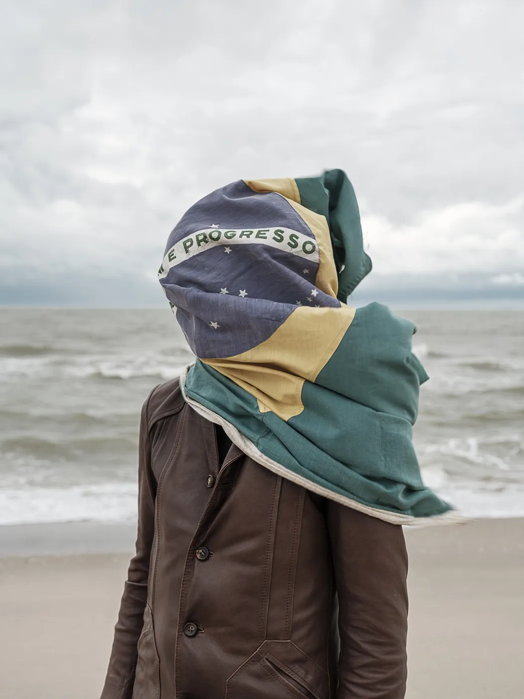 Persoon aan zee met een Braziliaanse vlag om het hoofd, foto van John Peters bij UNCOVER26
