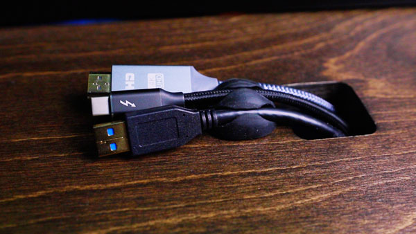 An image of a sticky cable clip being used to hold an HDMI cable, Thunderbolt 3 cable, and USB cable in place.