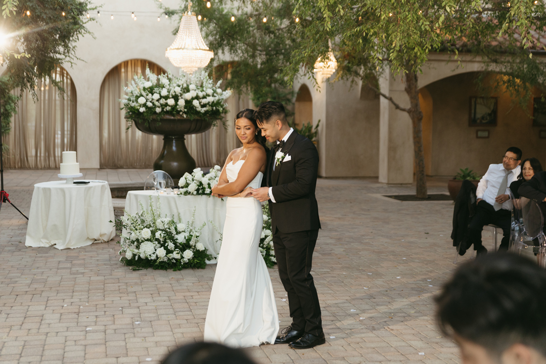 Bride and groom share their first dance in the Serra Plaza wedding venue Courtyard under sparkling chandeliers.