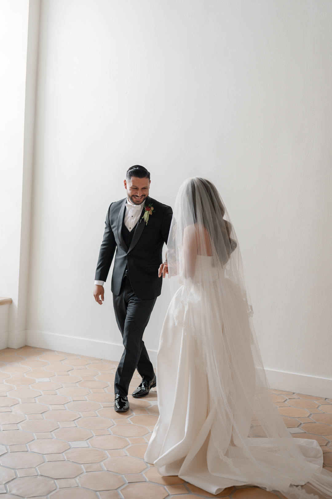 Groom smiles at bride as he sees her for the first time during their first look.
