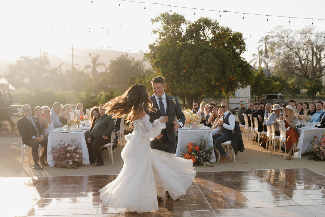 Groom twirls bride for golden hour first dance.