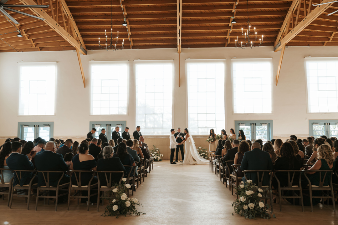 Bride and groom stand in front of guests inside Grand Gimeno for their wedding ceremony and vow exchange.
