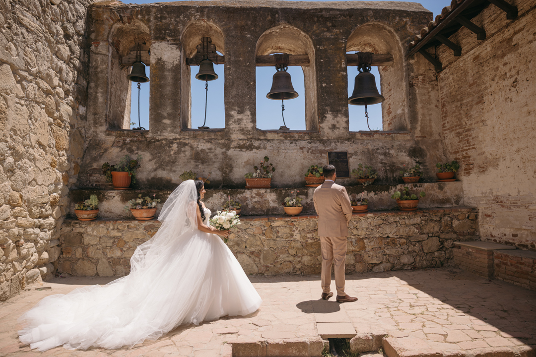 Bride approaches groom inside Mission San Juan Capistrano for their first look.