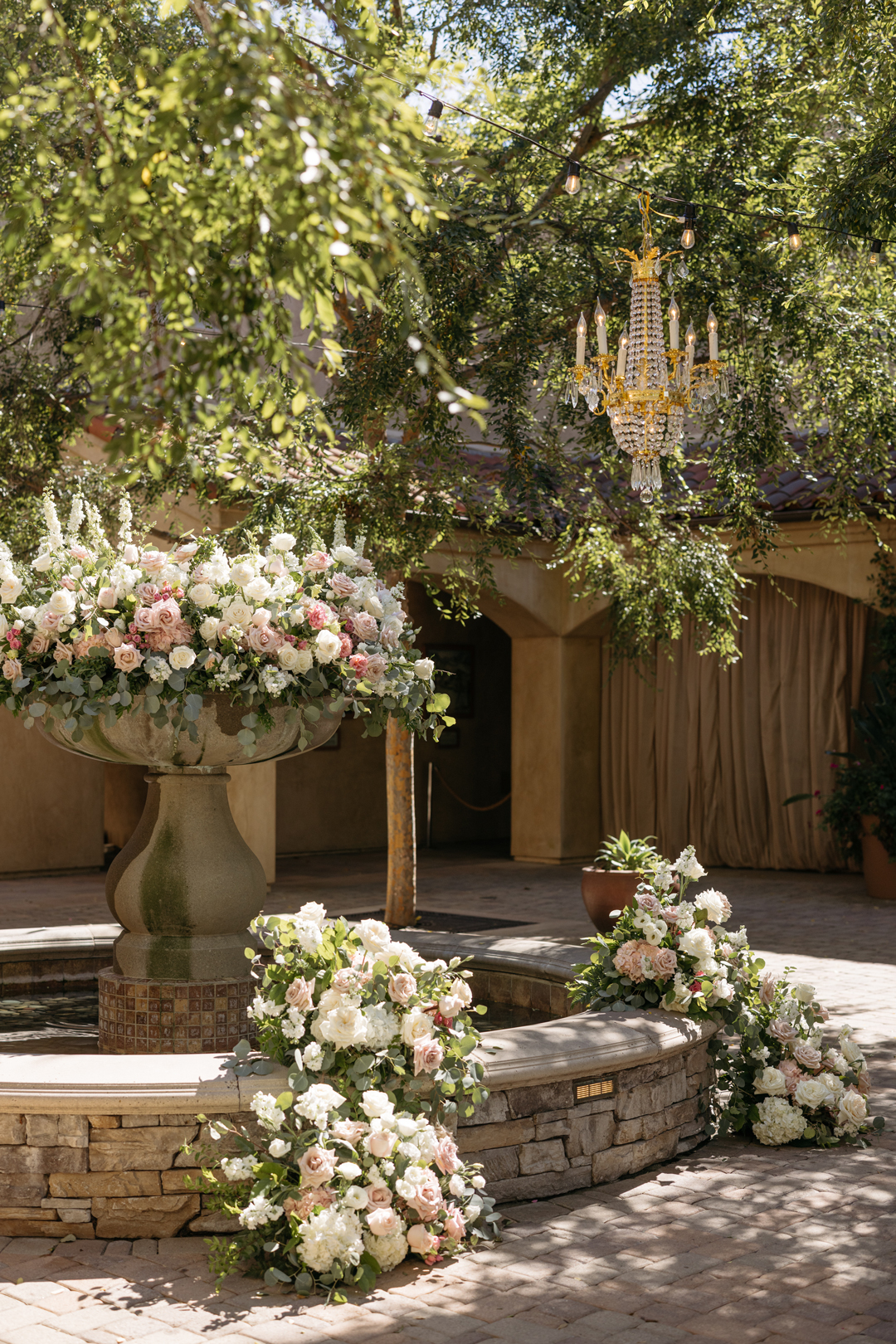 Blush florals decorate the Serra Plaza wedding venue Spanish fountain for an outdoor wedding ceremony.