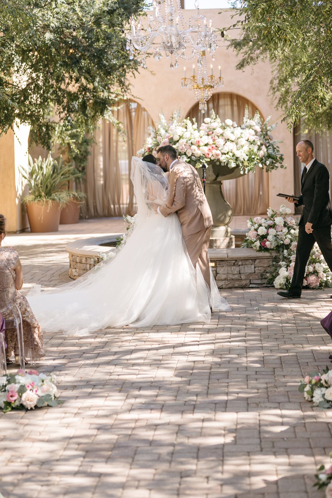 Bride and groom kiss during their outdoor wedding ceremony.