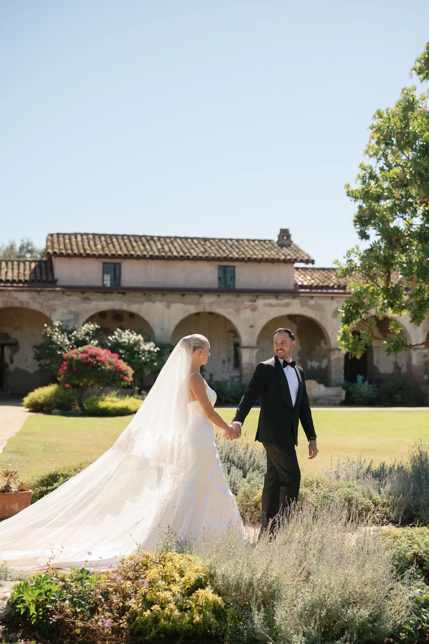Bride and groom walking in the Mission courtyard.