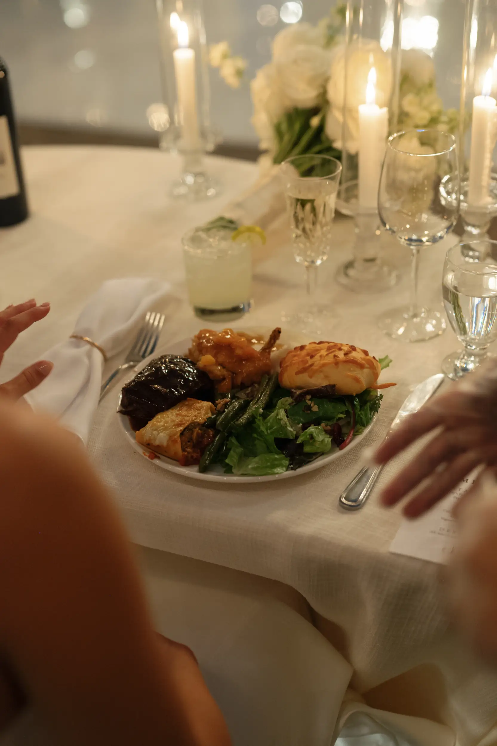Wedding dinner plate with chicken, beef, salad, potatoes, pasta, and a roll.