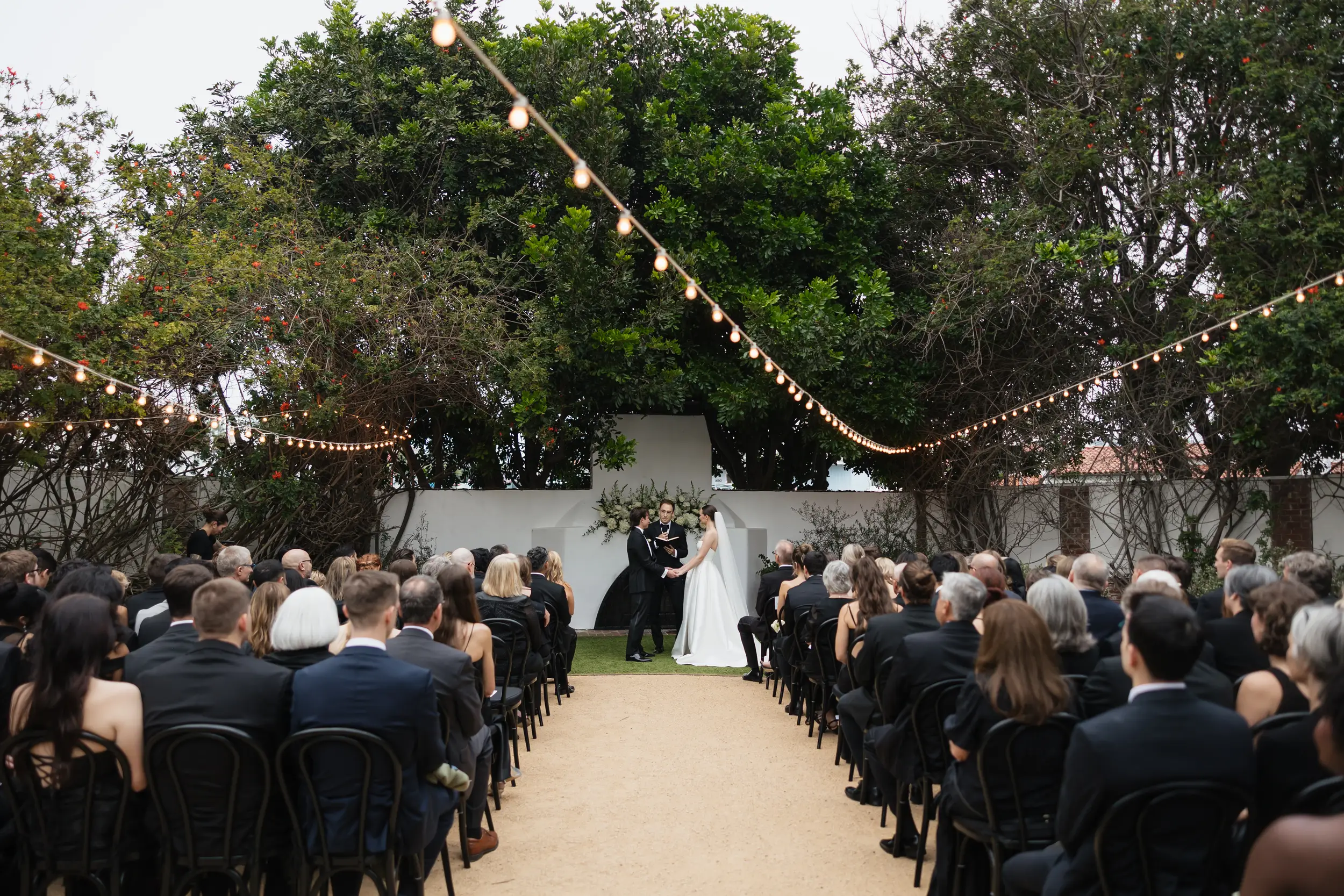 Bride and groom share vows in a garden-inspired courtyard by the California coast.