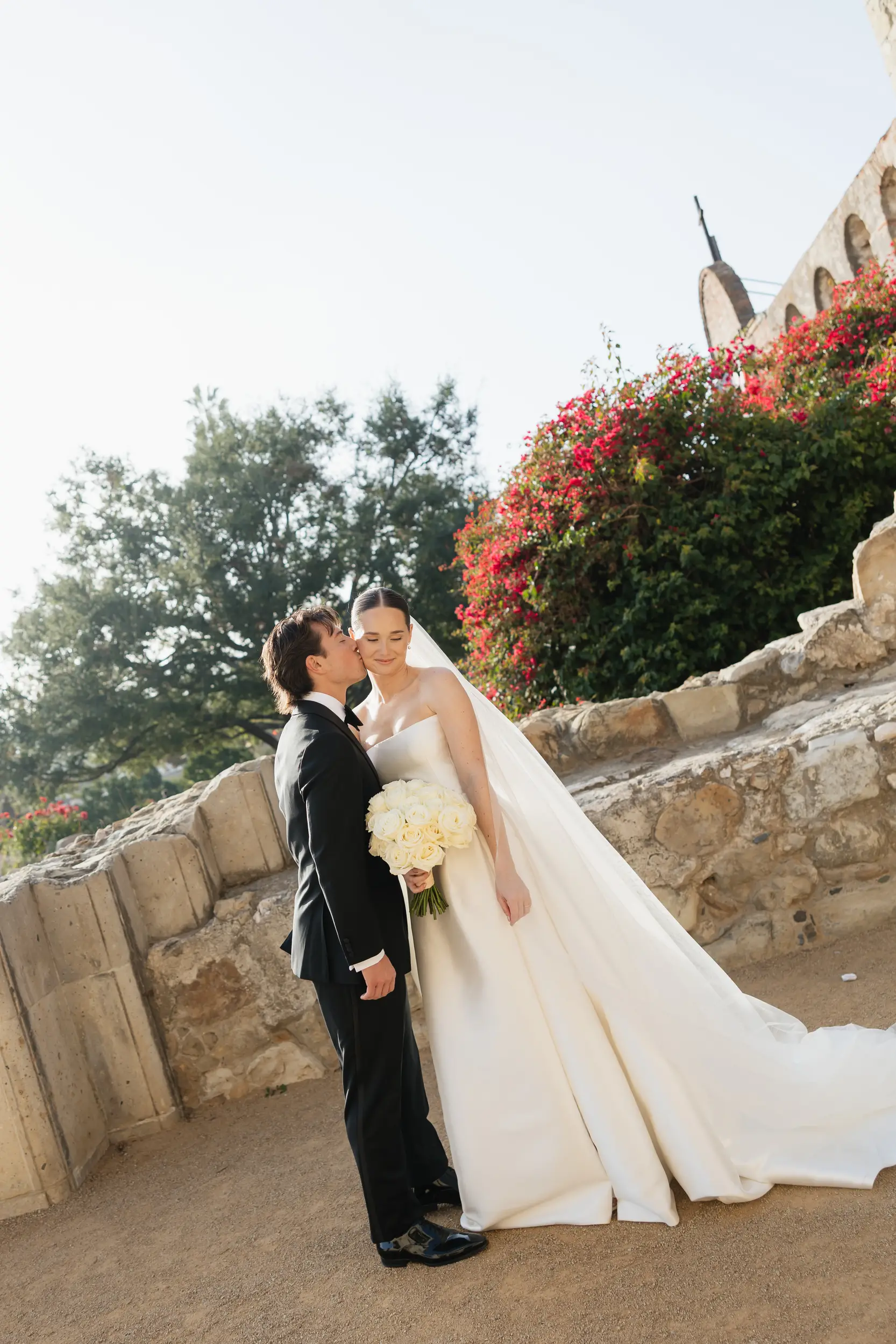 Groom kisses the bride's cheek inside Mission San Juan Capistrano for their first look.
