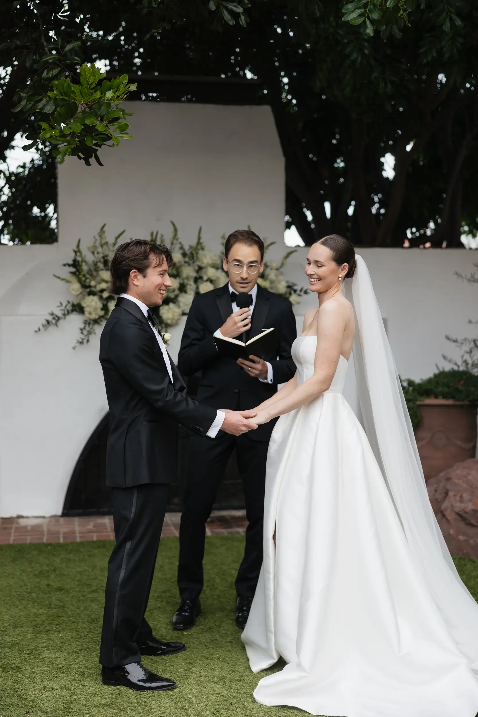 Bride and groom laugh while officiant makes a joke during the wedding ceremony.