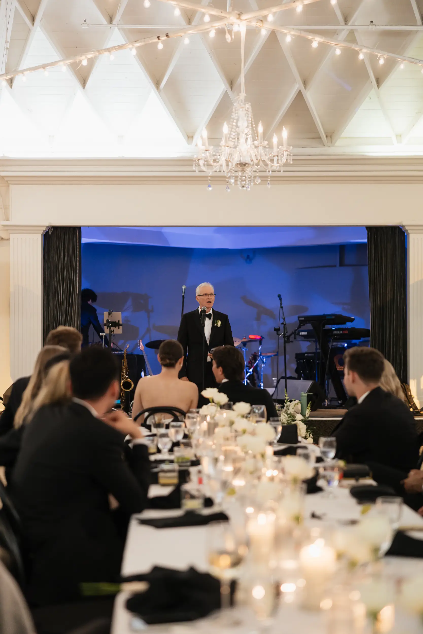 Family members share toasts as wedding guests listen from their seats.
