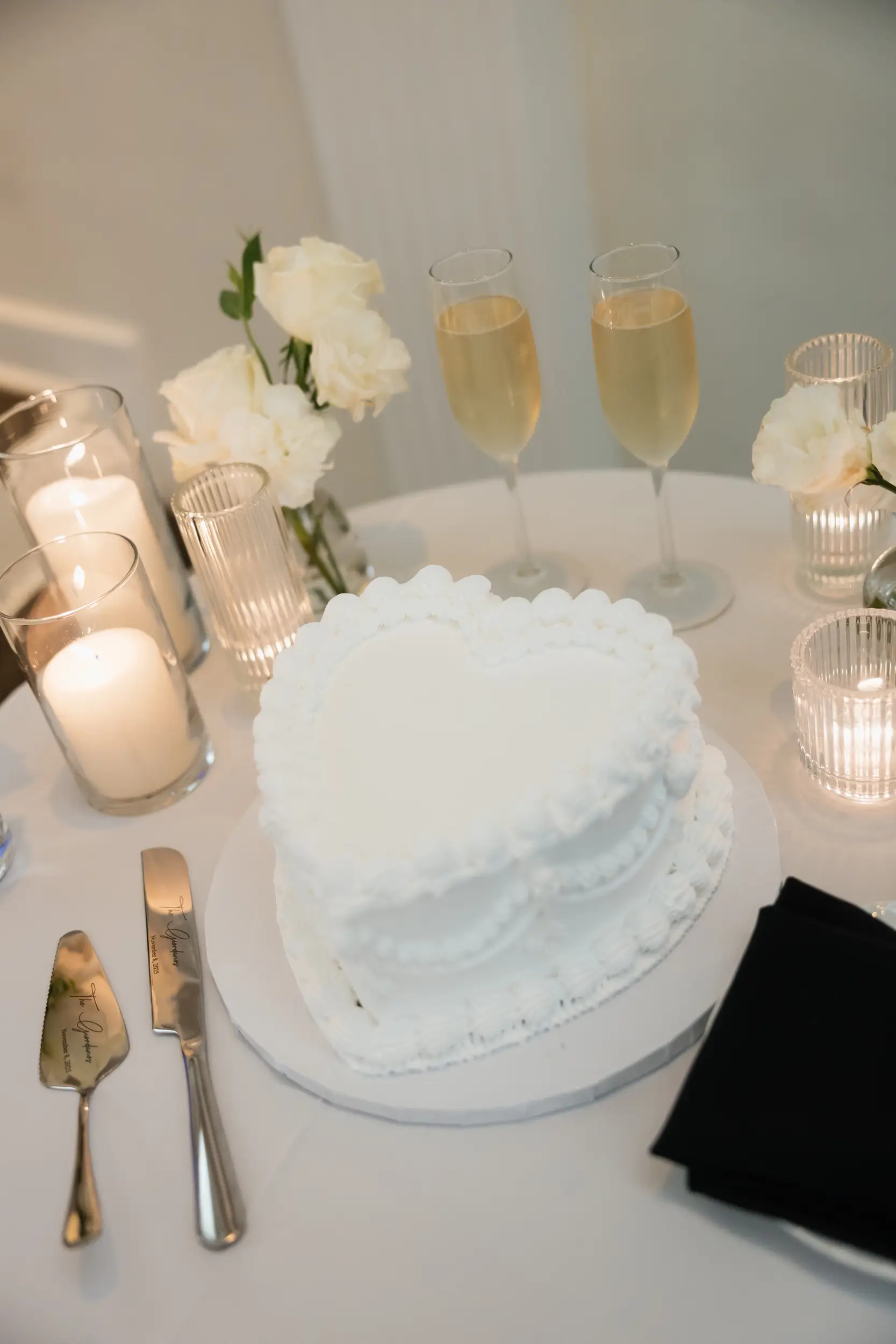 Cake table with champagne glasses and a white vintage heart wedding cake.