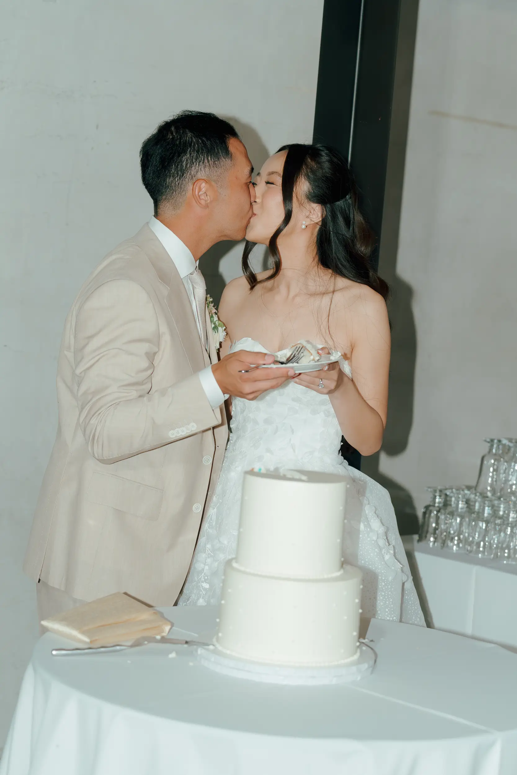 Bride and groom share a kiss after cutting into their wedding cake.