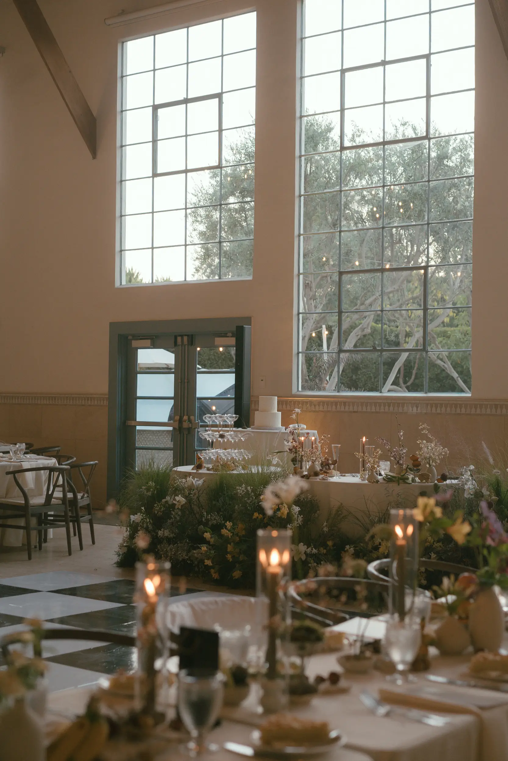 Sweetheart table decorated with flowers. A champagne tower and cake stand next to the table.