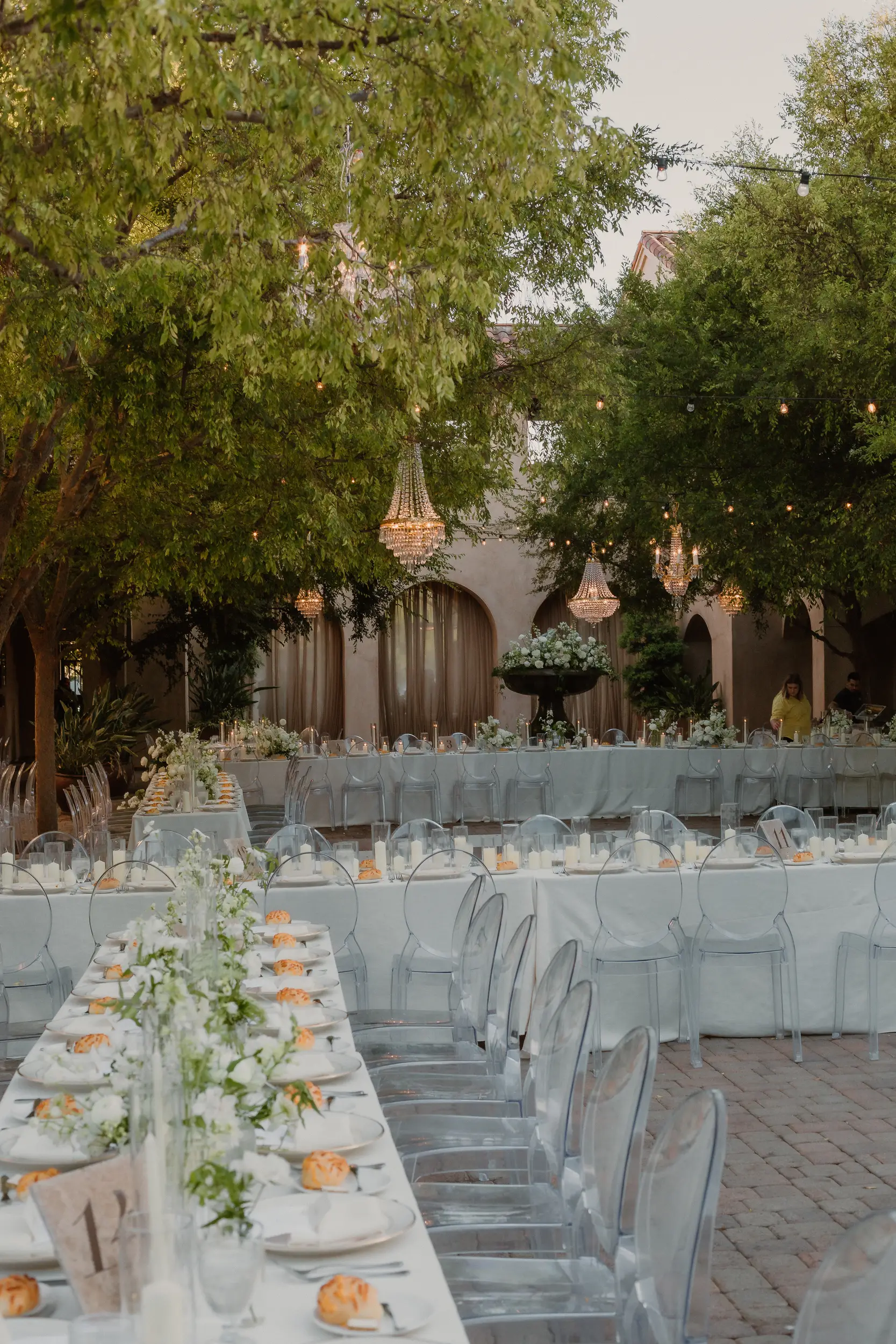 Outdoor courtyard wedding reception with chandeliers, checkered dance floor, and white florals.