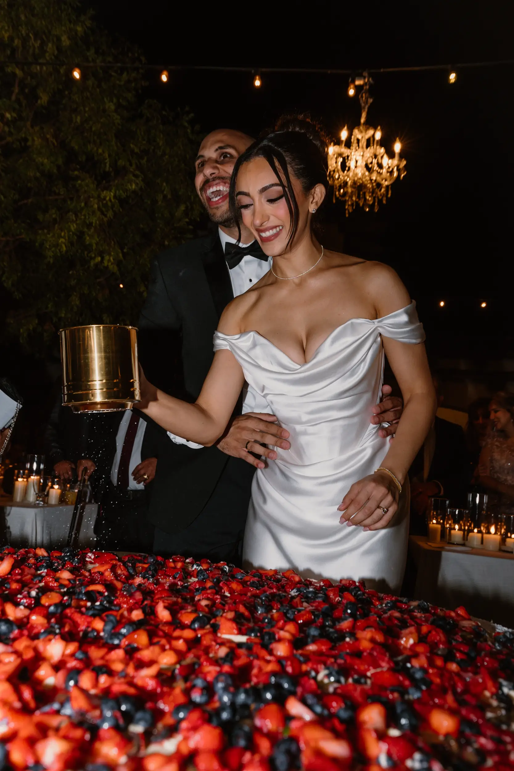 Bride and groom smile while they sift powdered sugar onto a 4-Foot millefoglie.