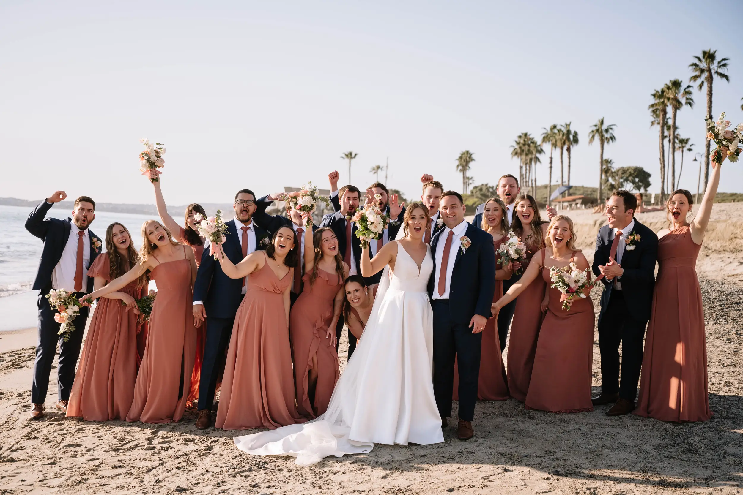wedding party cheer on the beach during cocktail hour.