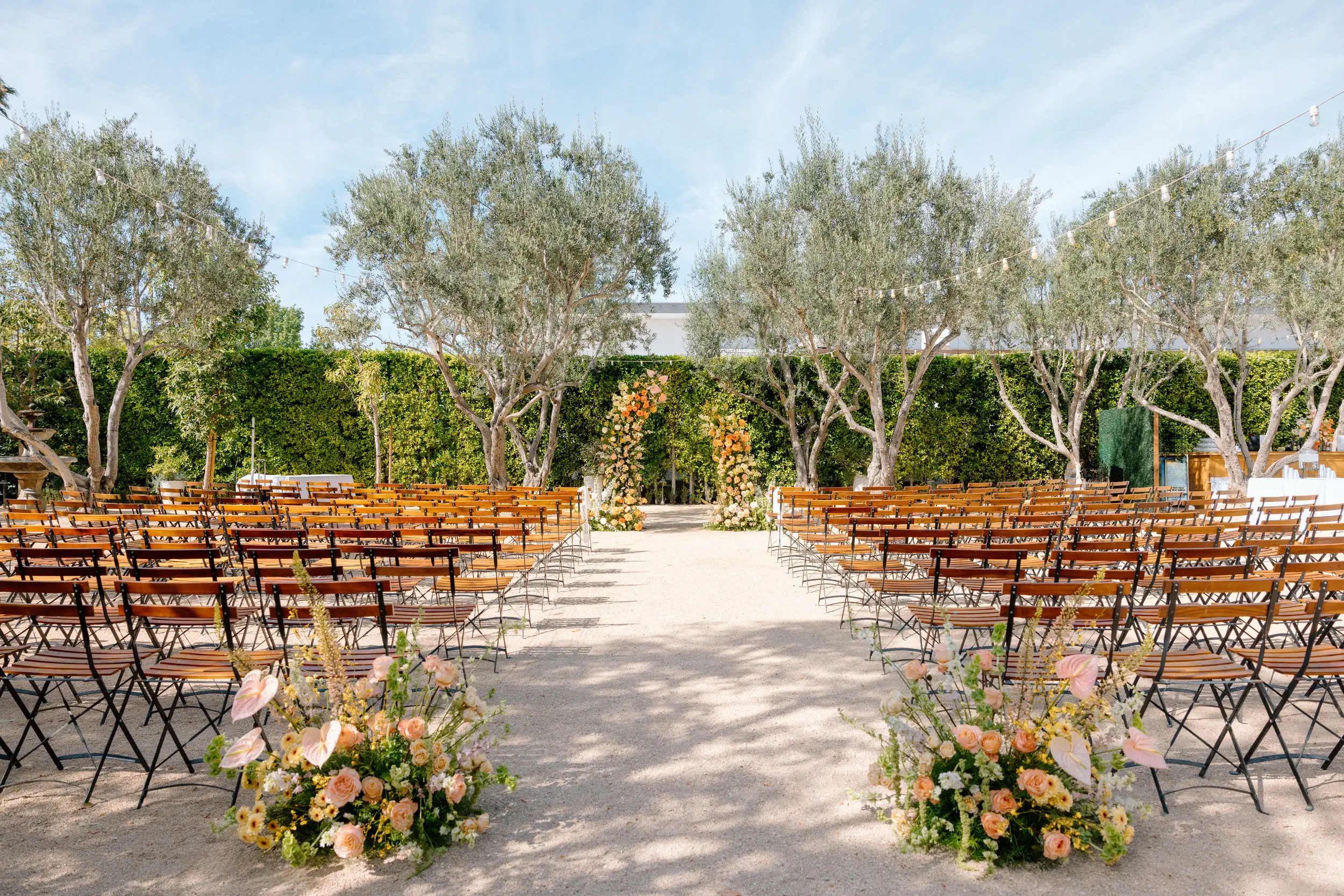 Orange, peach, and yellow florals decorate the Olive Grove for a spring wedding ceremony.
