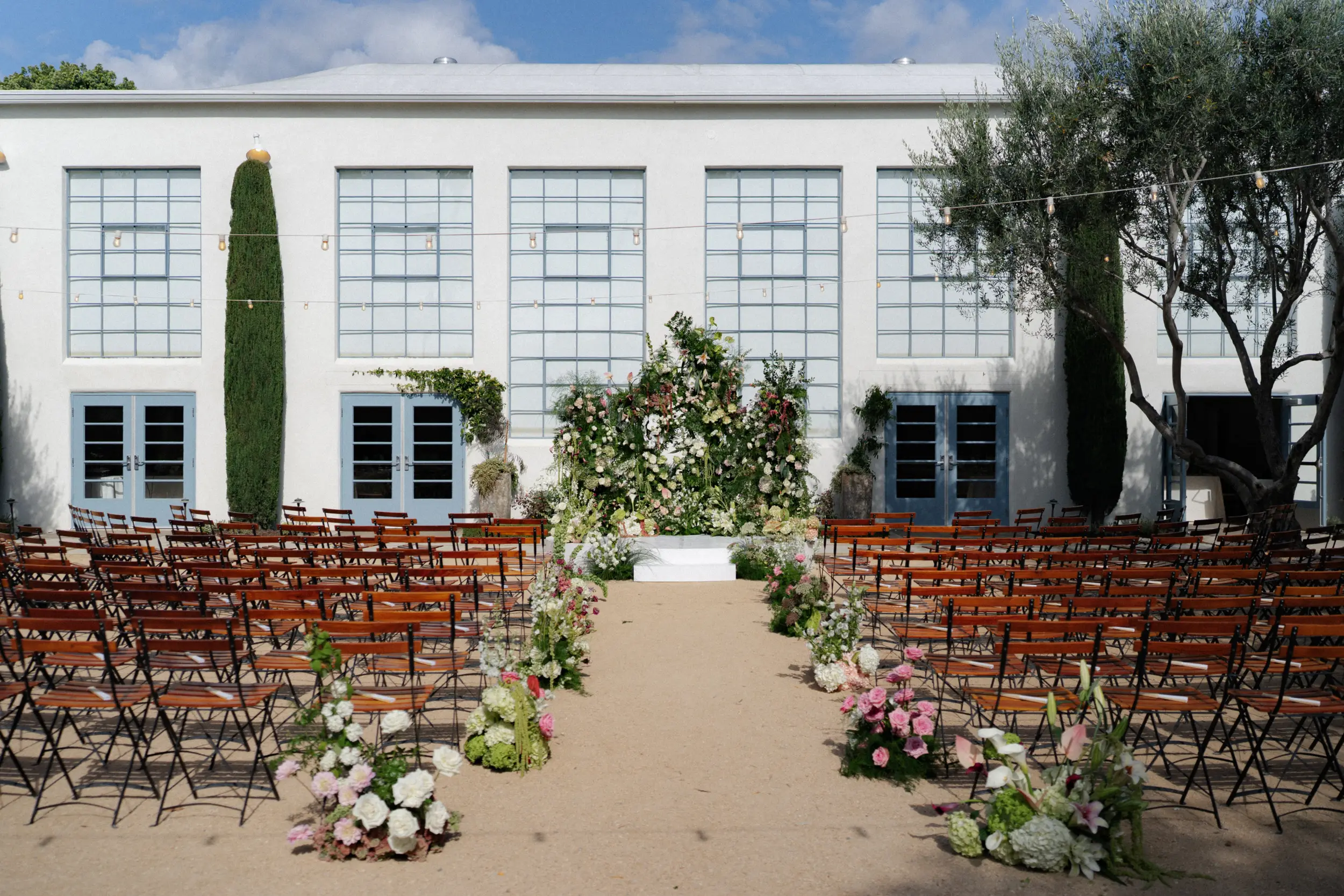 Outdoor wedding ceremony with floral backdrop.