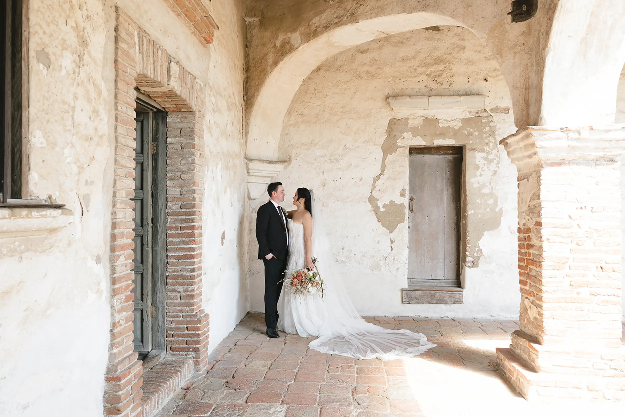 Bride and groom pose for photos at Mission San Juan Capistrano.
