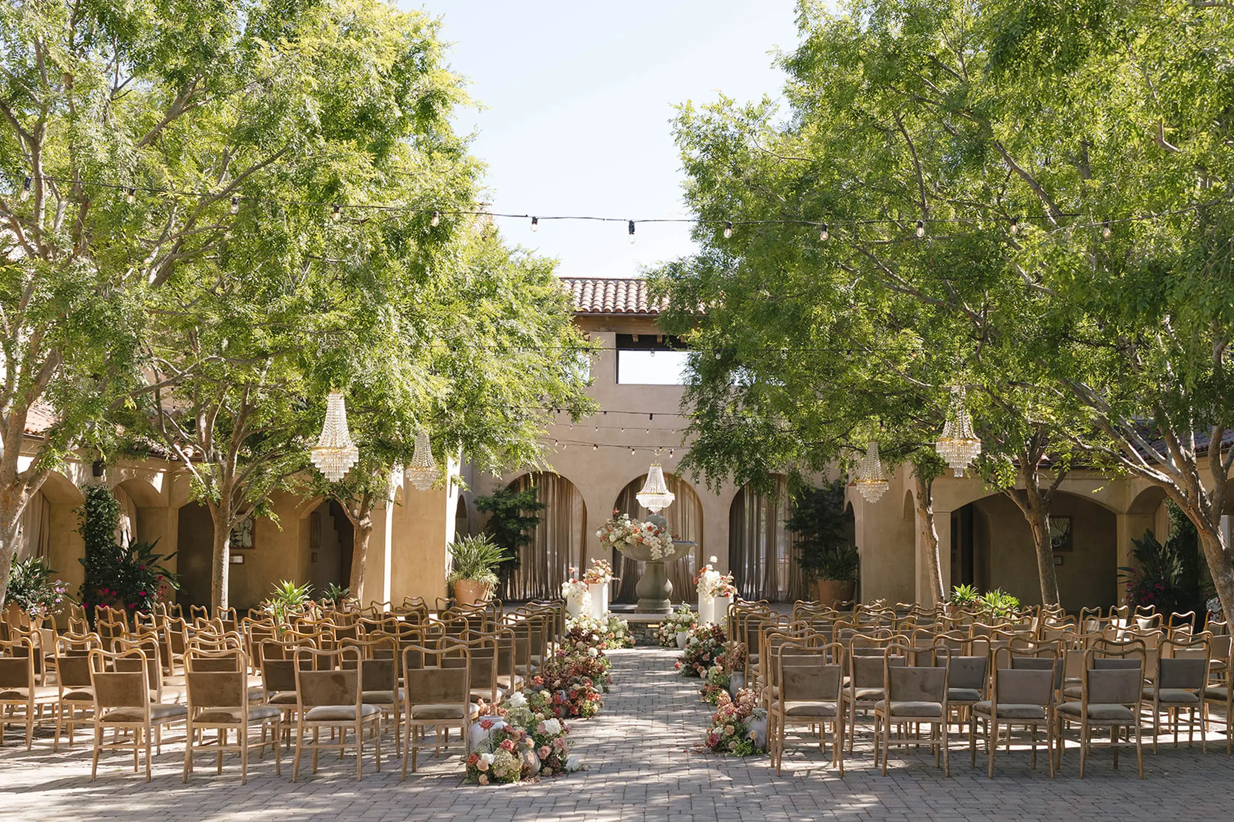 Blush and ivory florals decorate the Serra Plaza courtyard for this outdoor wedding ceremony in Southern California.