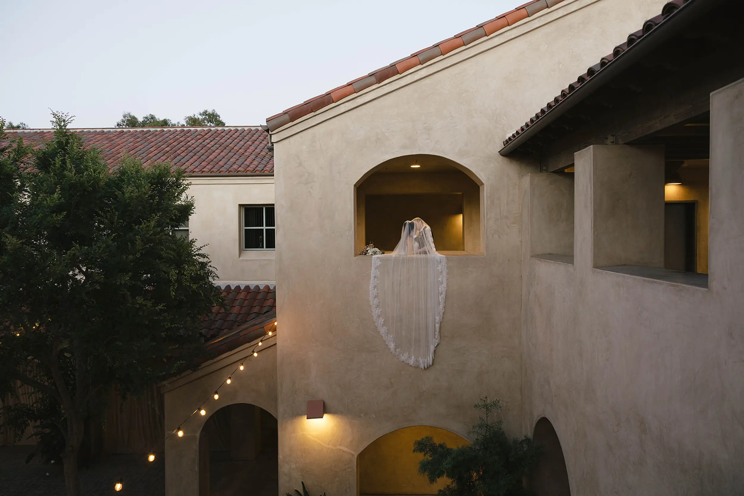 Bride and groom share a kiss from the second story at Serra Plaza.