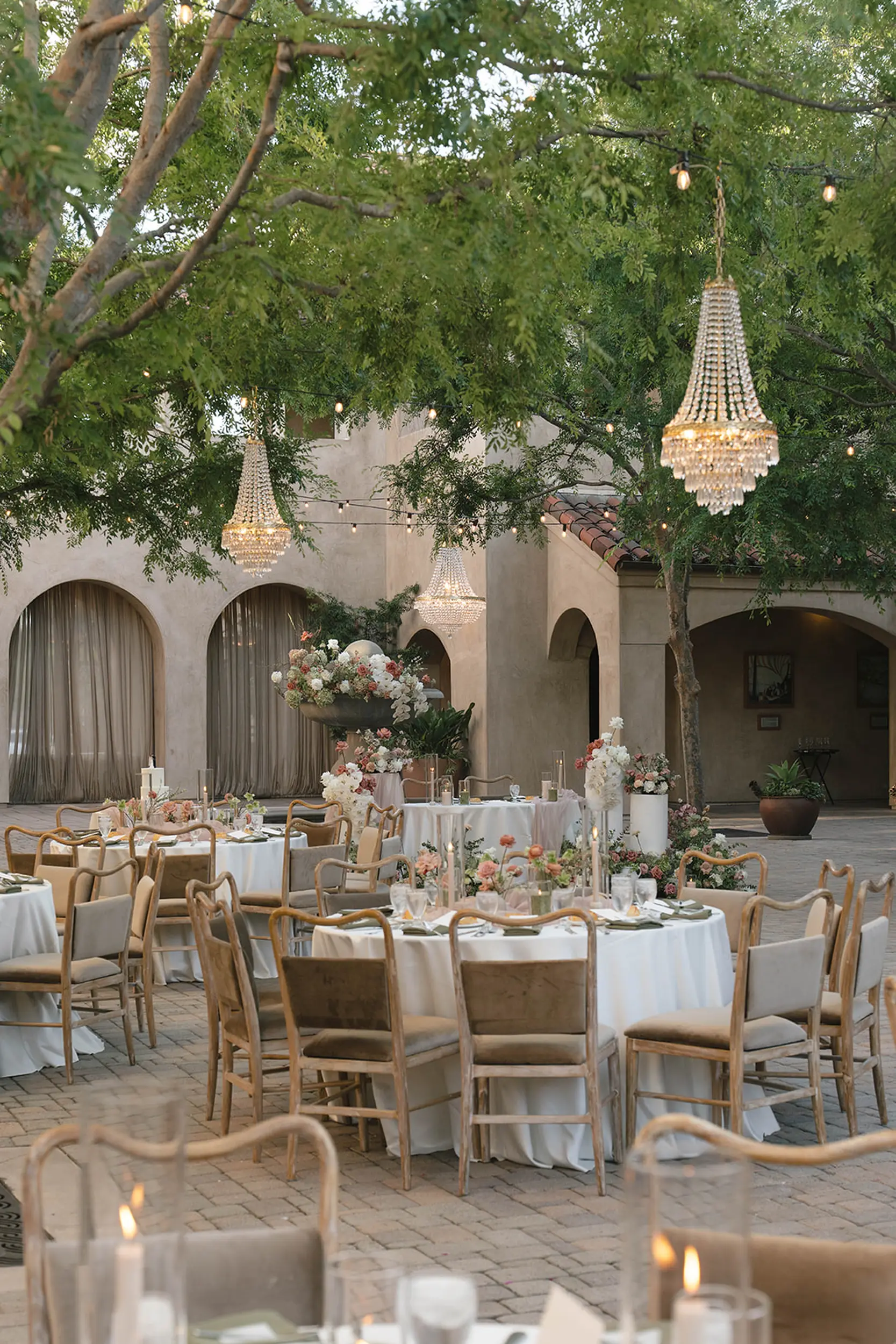 Blush and moss green florals decorate the outdoor courtyard for a wedding reception.