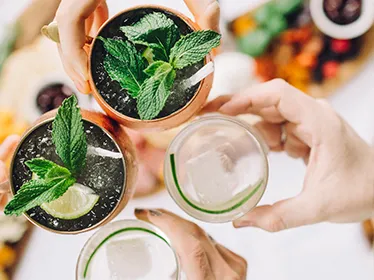 Guests raising cocktails garnished with mint and lime.