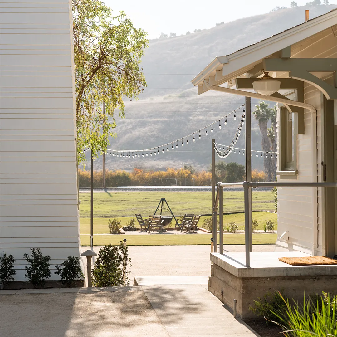 Porch and lawn at The Swanner House with string lights and hills beyond.