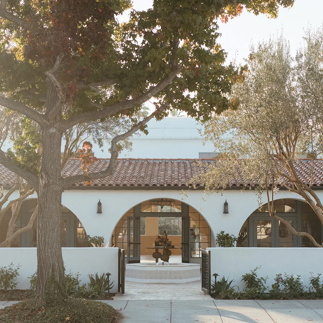 Arched entrance and courtyard fountain at Grand Gimeno beneath shade trees.