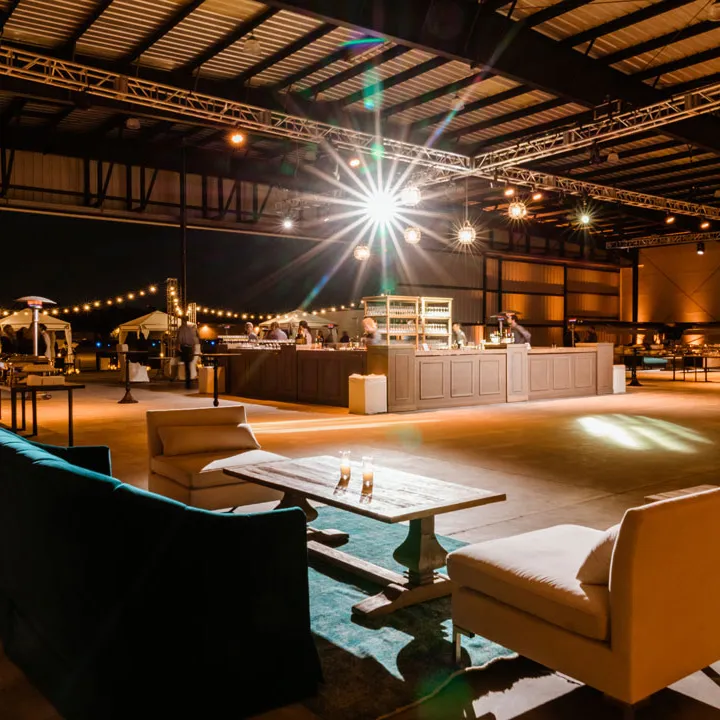 Lounge seating and bar beneath event lighting inside The Executive Hangar.