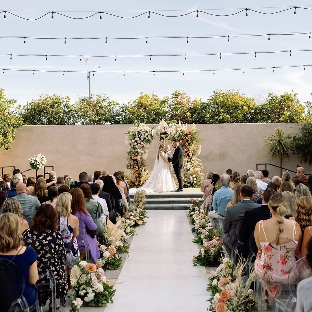 Outdoor wedding ceremony with a floral aisle and seated guests at Hangar 21 South.