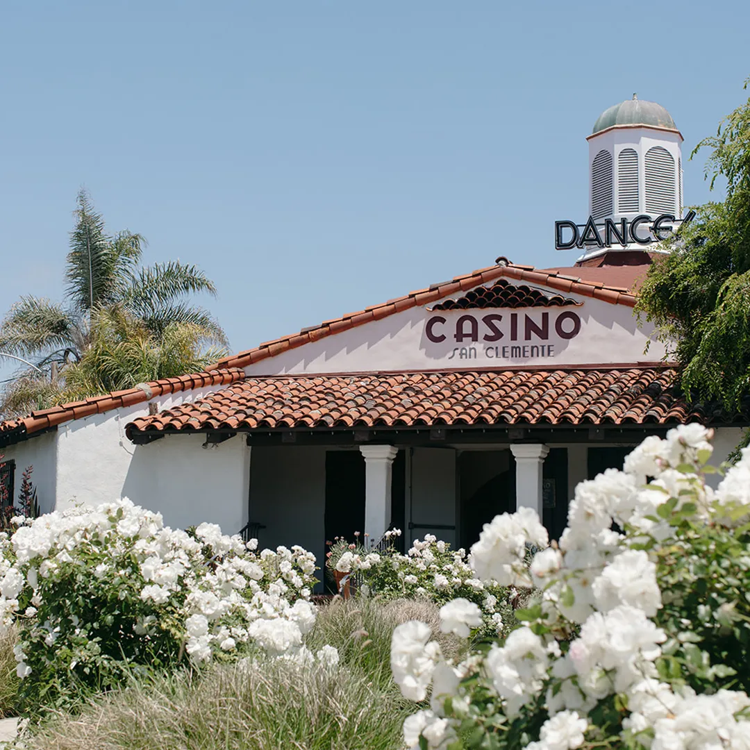 The Casino San Clemente exterior with tiled roofs, tower and white flowers.