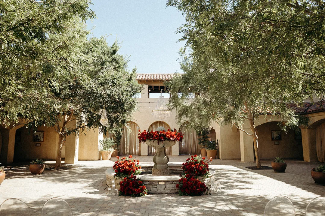 Red floral arrangements surrounding the fountain in Serra Plaza's tree-lined courtyard.