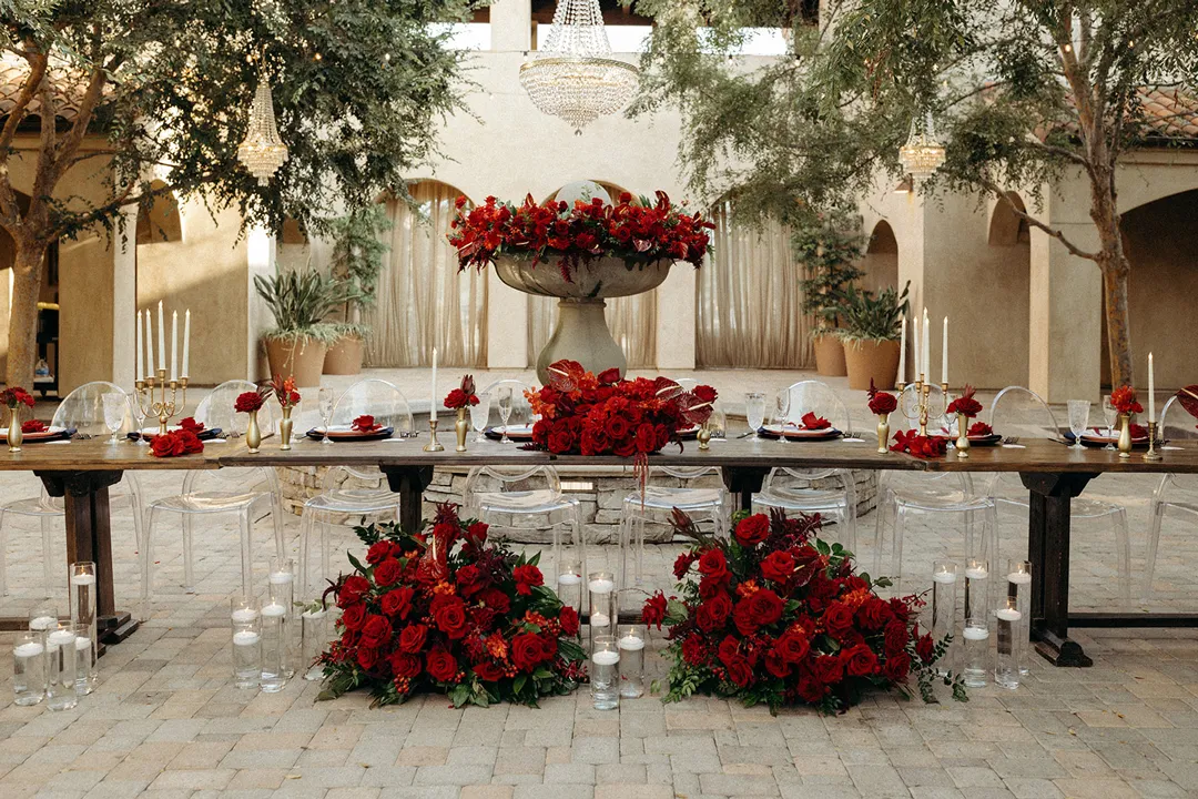 Long reception table with red flowers and candles in front of Serra Plaza's fountain.