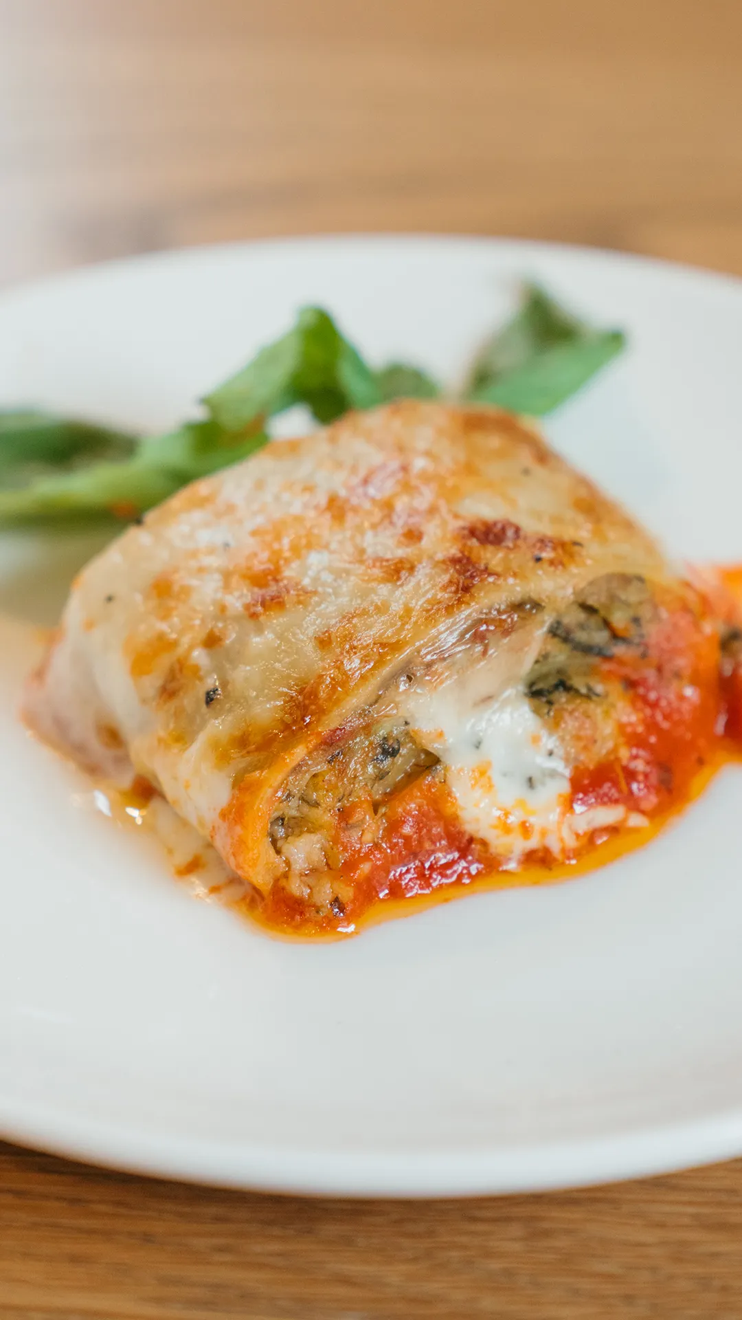 Baked pasta roll topped with melted cheese and tomato sauce.