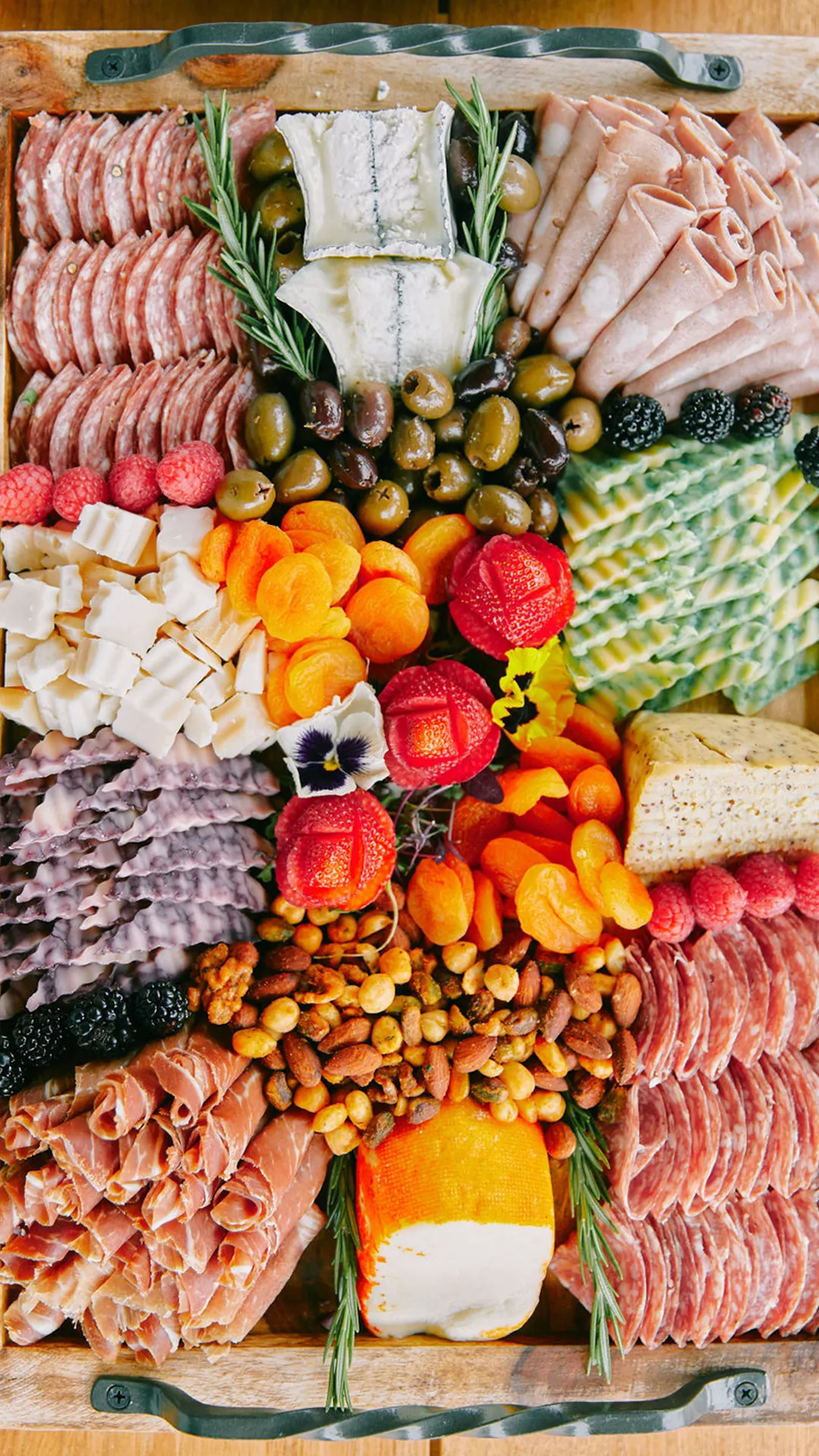 Charcuterie tray with sliced meats, cheeses, olives, nuts, fruit and crackers.