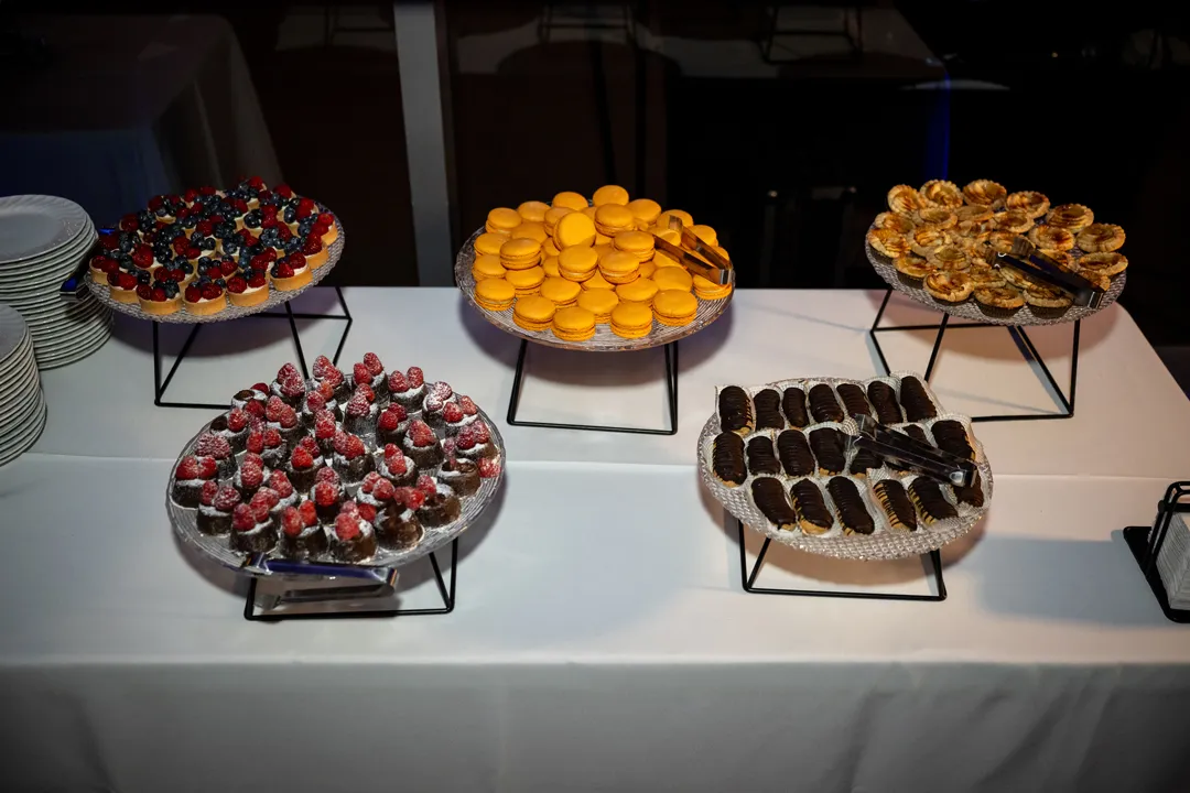 Miniature desserts, macarons and fruit tarts displayed on raised platters.