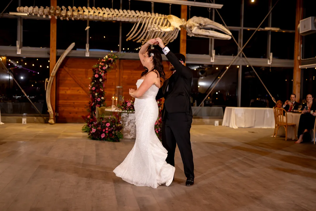 Wedding couple dancing beneath the suspended whale skeleton.