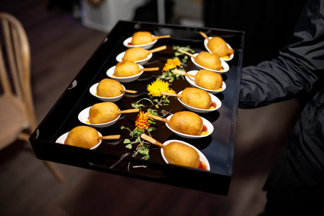 Golden bite-sized appetizers on tasting spoons with dipping sauce.