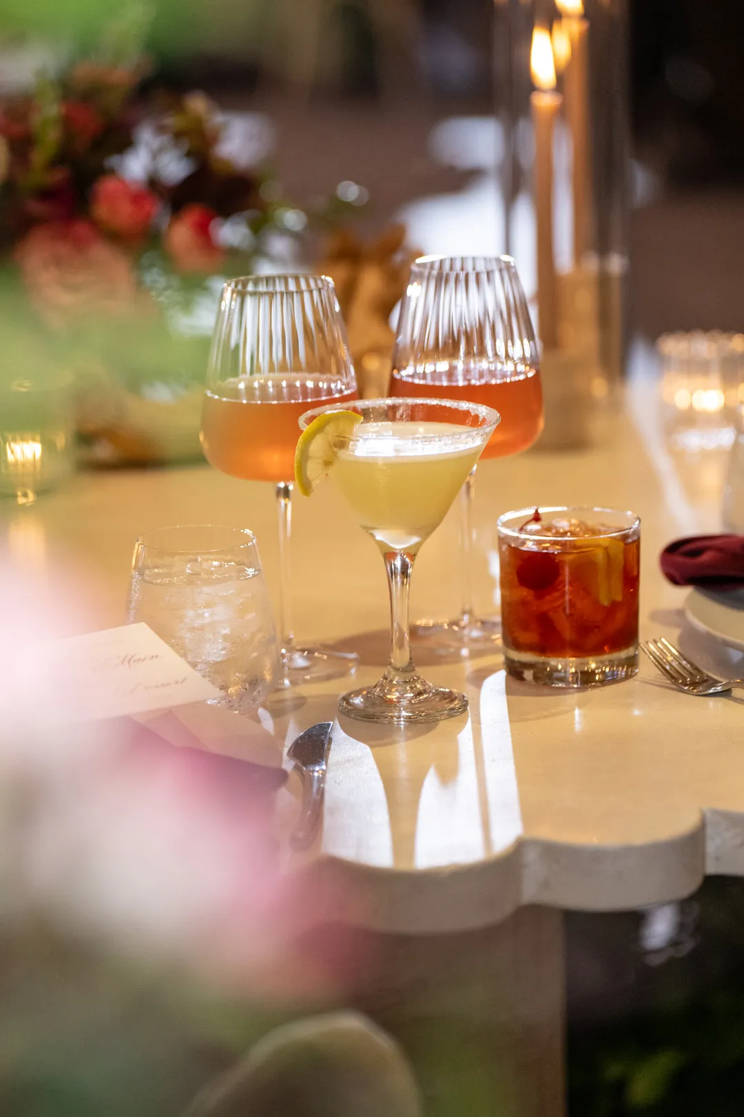 Assorted wedding cocktails displayed in stemmed glasses and a rocks glass.