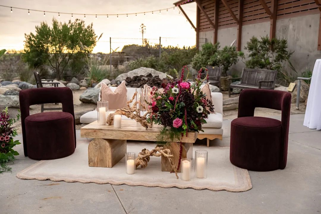 Plum-colored lounge chairs and a cream sofa around a flower-decorated wooden table.